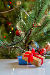 Gift boxes and blurred Christmas tree with twinkling party lights and toy balls.