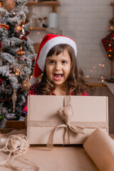 a happy little girl at home in the kitchen is packing Christmas presents in crab boxes. new year's sale