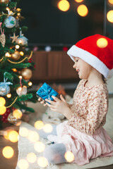 Happy little girl with gift box near the Christmas tree