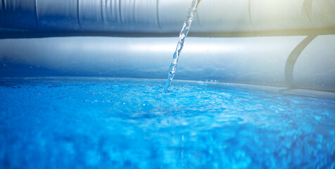 A stream of clean water pours into an inflatable pool. To collect water for bathing the child....