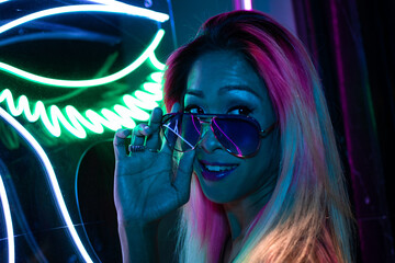 Teenage asian girl in sun glasses in neon light
