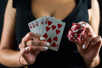 happy beautiful woman in a seductive dress plays poker at the casino table.