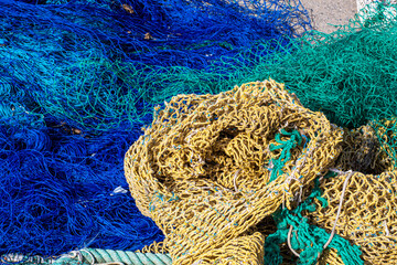 Cuerdas y redes de pesca de varios colores en el suelo del pequeño puerto pesquero del pueblo...
