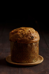 .Panettone, typical Christmas italian cacke, on wooden dark stage. Front view. Copy space.