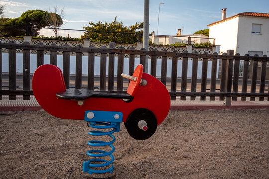 Peque&ntilde;o cochecito rojo del parque infantil para columpiarse los ni&ntilde;os con la vaya de madera de fondo. 