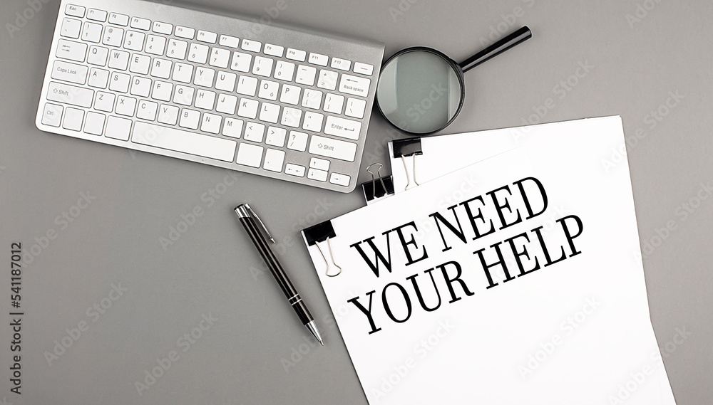 Poster we need your help text on paper with keyboard on grey background