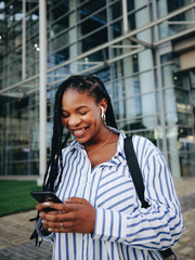 Fototapeta premium Black business woman using a smartphone while commuting in the city