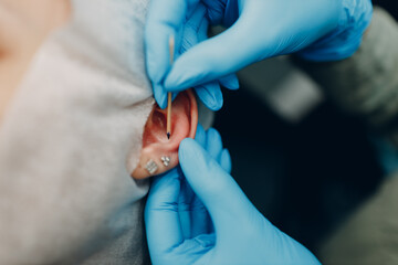 Young woman doing ear piercing at beauty studio salon close up ear