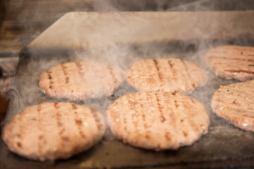 Burgers on the grill plate, fuming food, fresh food, street food. 