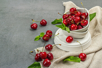 Ripe sweet cherries with fresh mint leaves, traditional summer fruits. Trendy stands, vintage napkin