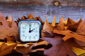 Clock with autumn leaves. Winter hour. 3 o'clock becomes 2 o'clock.