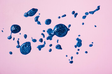 Blue glitter abstract drops and smear on colored background top view. Christmas glitter element