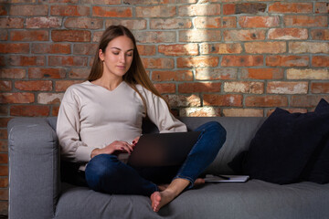 Woman on couch with a laptop and notebook
