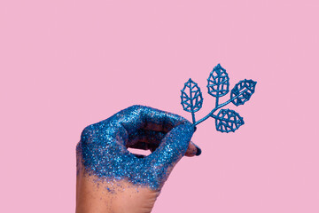 Creative Christmas concept of female hand with blue glitter and glitter twig on color background