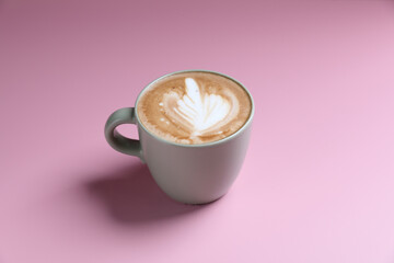 hot cappuccino with latte art isolated in pink background