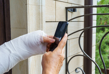 Woman hand in white plaster cast holds mobile phone