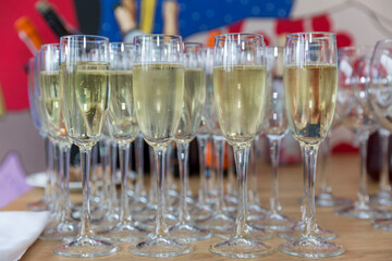 Row of glasses with champagne on the festive table. Celebrations and holidays. Front view.
