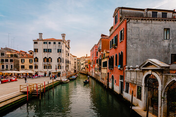 Venetiaanse gondel terwijl deze vaart op het karakteristieke kanaal met kleurrijke gebouwen bij zonsondergang