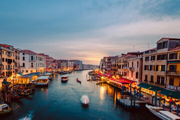 Fototapeta na wymiar View of Venice's Grand Canal at sunset with illuminated venues on the shores and boats crossing it
