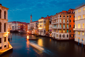 View of Venice's Grand Canal at sunset with illuminated historic buildings and light trails of tourist boats