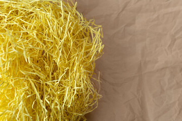 Closeup decorative Shredded yellow color craft paper inside gift box texture on creased brown wrap paper background