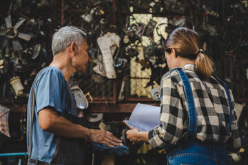mechanic technician team wearing uniform reading or writing clipboard document and standing in auto repair shop garage, with car vehicle background, job of auto garage service concept