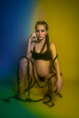 Obraz premium Beautiful pregnant woman with braids in color photoshoot