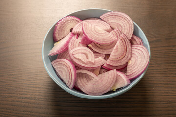 Obraz na płótnie Canvas cut raw red onion in blue bowl on the kitchen table
