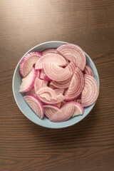 cut raw  red onion in blue bowl on the kitchen table