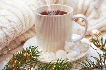 Winter, Christmas, New Year decorations composition, concept, background. White Mug, cup of tea, coffee, steam, meringue, knitted plaid. Christmas lights. Christmas mood morning. Christmas  card.