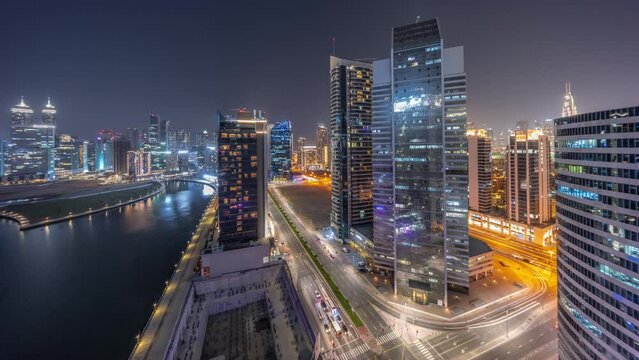 Cityscape of skyscrapers in Dubai Business Bay with water canal aerial day to night transition timelapse. Modern skyline with towers and road traffic after sunset. A center of international business