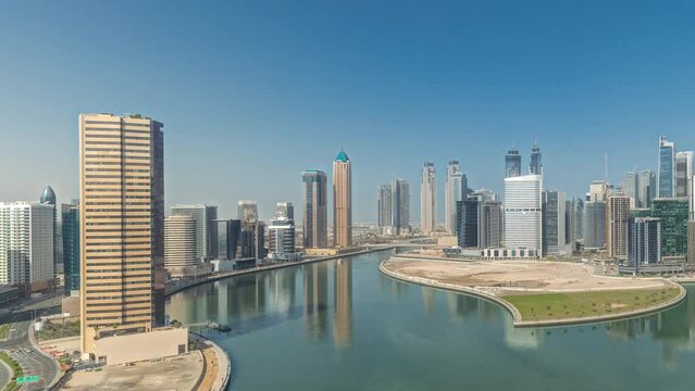 Panorama showing cityscape skyscrapers of Dubai Business Bay with water canal aerial timelapse. Modern skyline with towers and waterfront. A center of international business