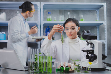 Female scientists' hand is holding a test tube with herb in laboratory. Concept of environmental biochemistry plants and herb laboratory, Eco beauty serum, organic cosmatic and skin care product.