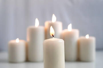 Fototapeta na wymiar Large burning wax candles on a white background.