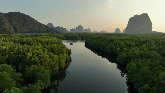 Drone shot tracking a boat on a river in the mangrove forest, Thailand