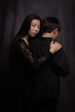 asian girl and boy, sister and brother in classic fine art dark studio portrait