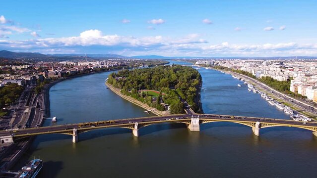 Slow aerial flight showing traffic on Arpad Bridge and idyllic Margaret Island with trees surrounded by Danube River in Budapest,Hungary