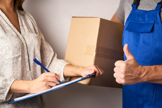 Delivery man giving cardboard box to female hand