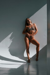 Fototapeta premium Sportive body type. Young woman in underwear is in the studio