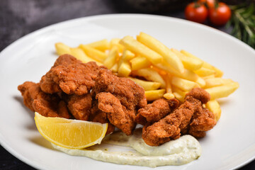 Portion of schnitzel with french fries, garnish on the wooden table