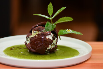 Chocolate ball with mint with warm sweet sauce in a plate on the table
