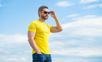 man in yellow shirt and sunglasses outdoor on sky background. summer fashion