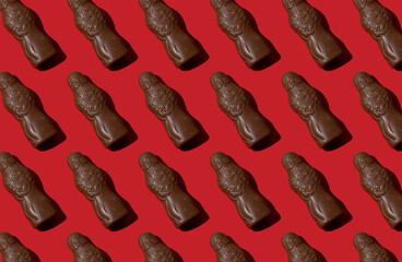 Pattern chocolate Santa Claus figure on a red background. Sweet Christmas candy. Close up sweet food for the holiday. Treat. Saint Nicholas chocolate figurine.