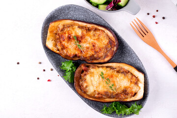 Stuffed eggplant halves with roasted vegetables, champignons and cheese served on the gray plate. Hot vegetarian meal. Top view
