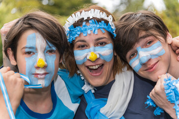 Madre e hijos maquillados con los colores del equipo Argentino de futbol, listos para alentar al seleccionado en cada partido.  - obrazy, fototapety, plakaty
