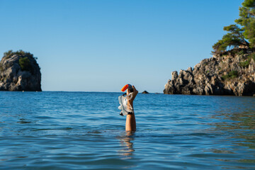A man holds a snorkel mask in his hand in blue sea. Diving mask in a man's hand. Photo of a mask and snorkel for swimming in a pool or sea
