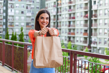 Woman delivering food in paper bag.Female volunteer holding groceries in the house porch. Delivery...