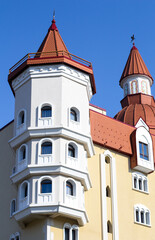 beautiful tower of  small castle against the blue sky. Architecture of buildings. Red cone-shaped roof. Arched windows.