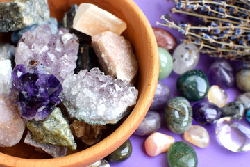 Semi-precious stones in a wooden bowl with a dry lavender bouquet. Amethyst and amethyst druse...