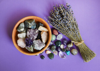 Semi-precious stones in a wooden bowl with a dry lavender bouquet. Amethyst and amethyst druse...